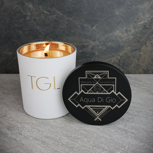 White candle with gold interior and black coaster on a gray surface with dark background