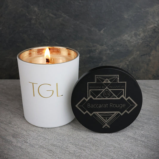 White candle with gold interior and black lid featuring geometric design on a gray surface. Baccarat Rouge candle natural soy beeswax blend 8oz Soy Candles by The GOOD LIFE
