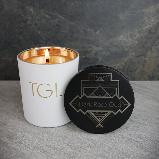 White candle with gold interior and black coaster on a gray surface