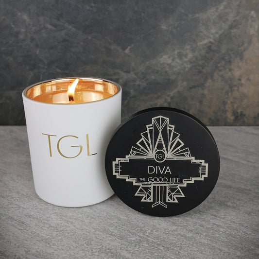 White candle with gold interior and black coaster on a gray surface