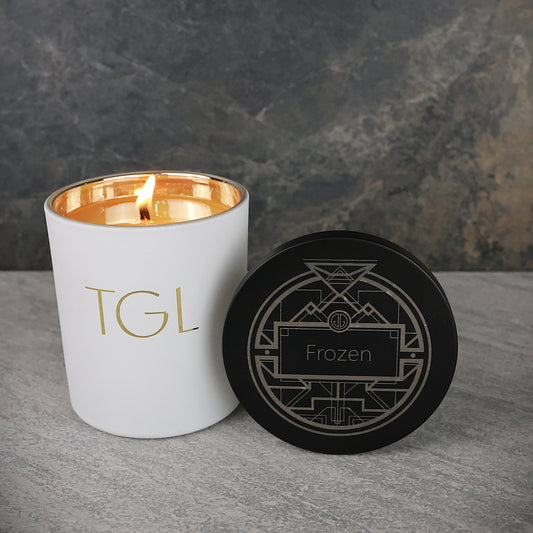White candle with gold interior and black coaster on a gray surface