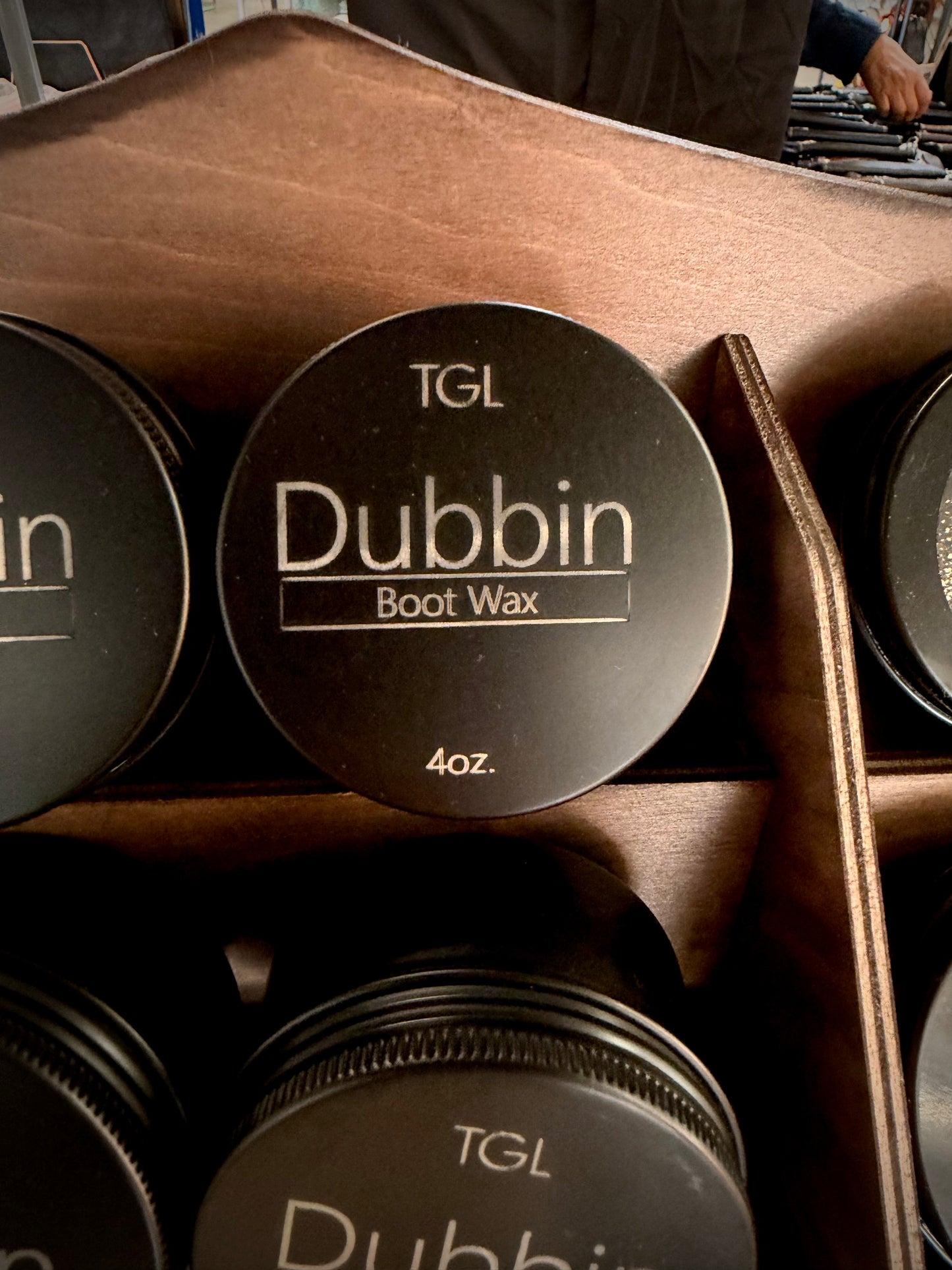 TGL Dubbin boot wax tins lined up in a display tray.