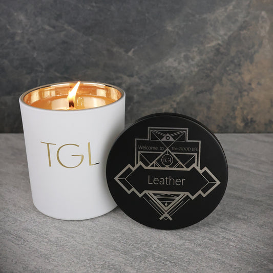 White candle with gold interior and black coaster on gray surface