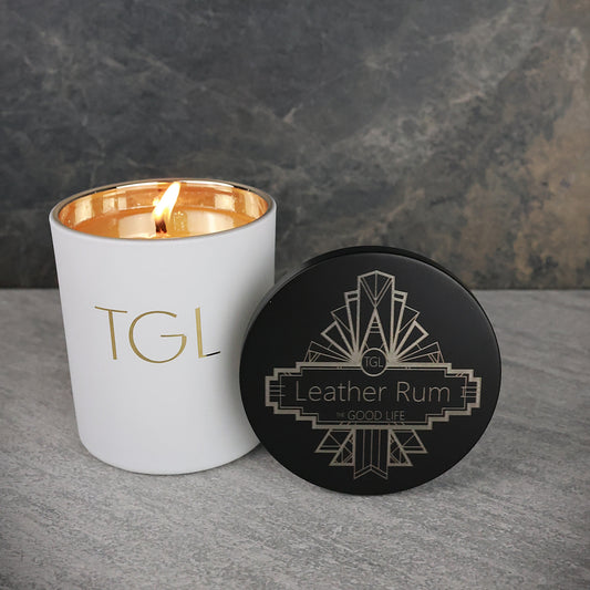 White candle with gold interior and black coaster on a gray surface