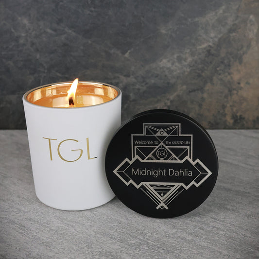 White candle with gold interior and black coaster on a gray surface