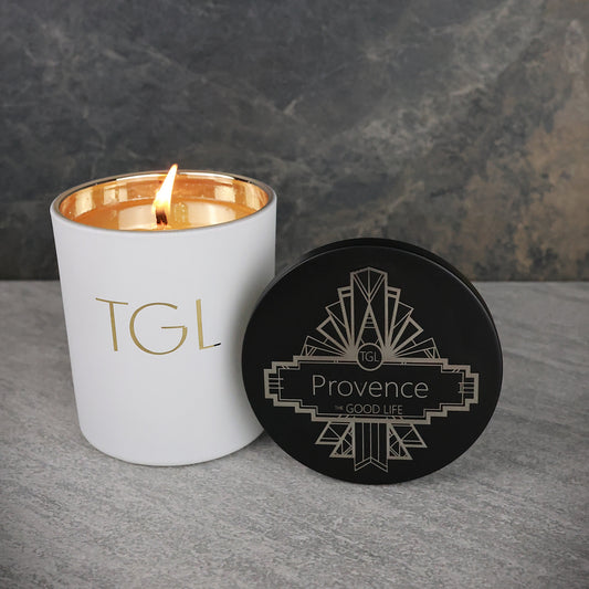 White candle with gold interior and lid labeled 'Provence' on a gray surface.