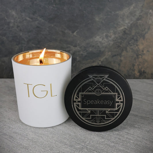White candle with gold interior and black coaster on a gray surface