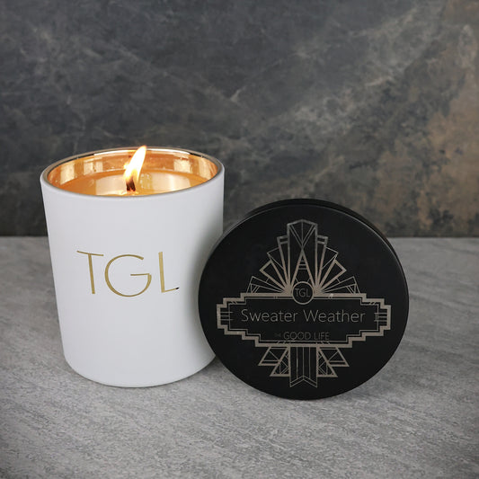 White candle with gold interior and black coaster on a gray surface