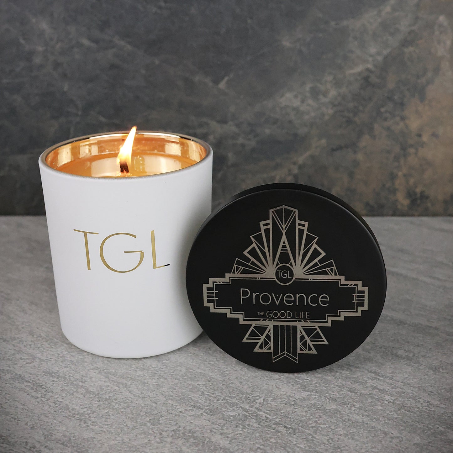 White candle with gold interior and lid labeled 'Provence' on a gray surface.