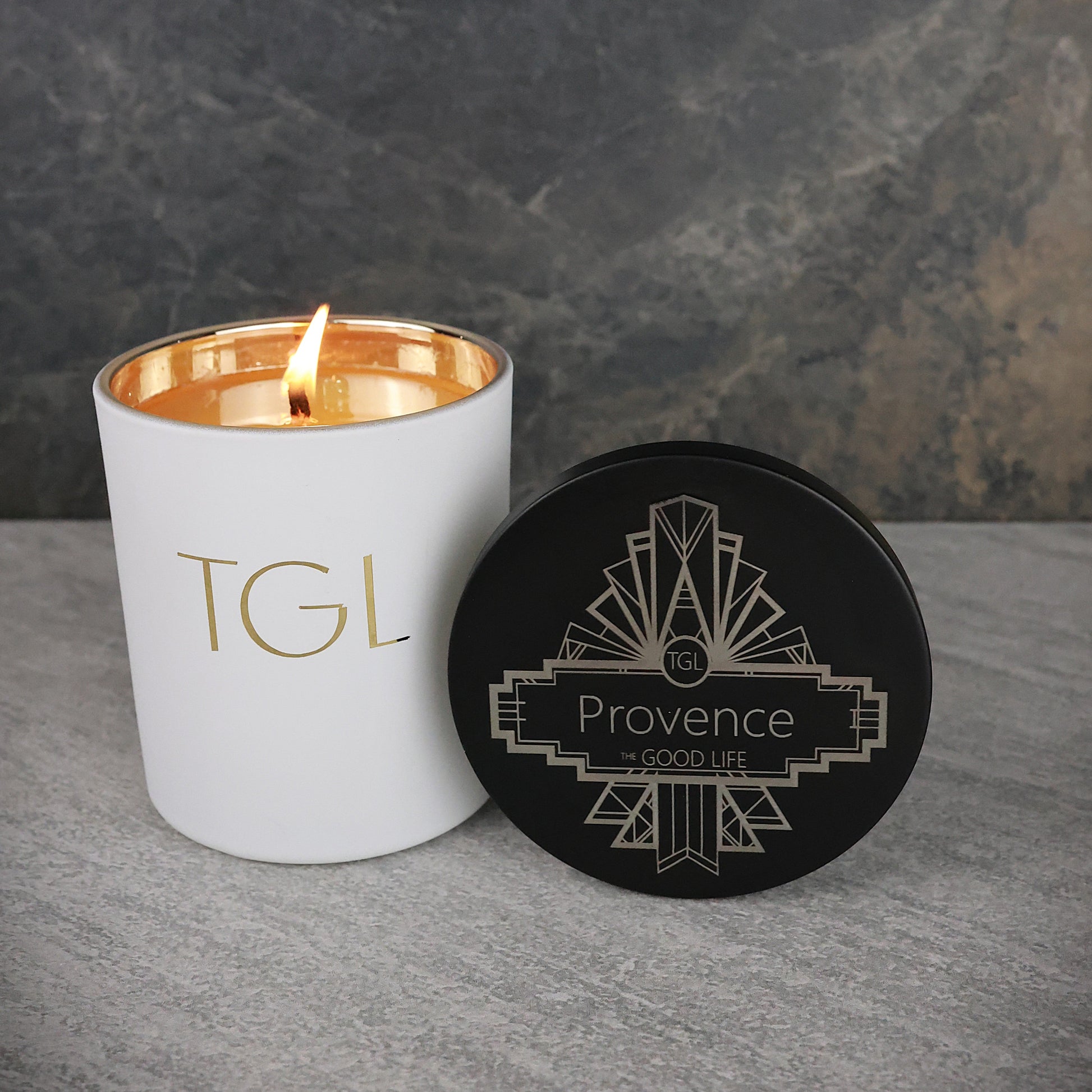 White candle with gold interior and lid labeled 'Provence' on a gray surface.