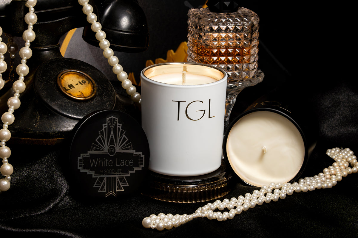 White Lace soy candle beside its engraved Art Deco lid, with pearls and a crystal perfume bottle