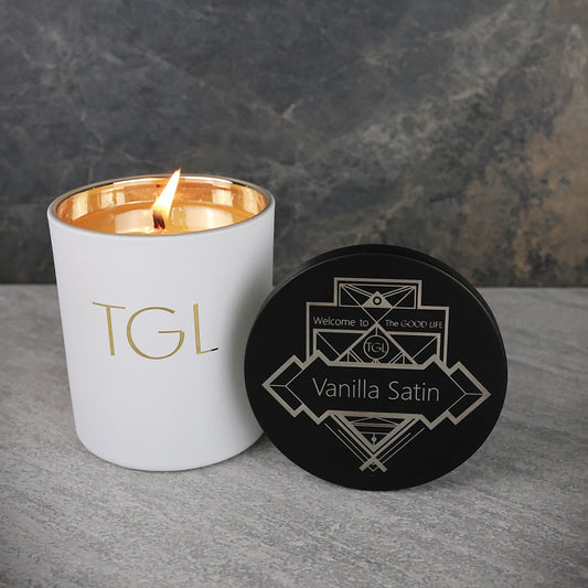 White candle with gold interior and black coaster on a gray surface
