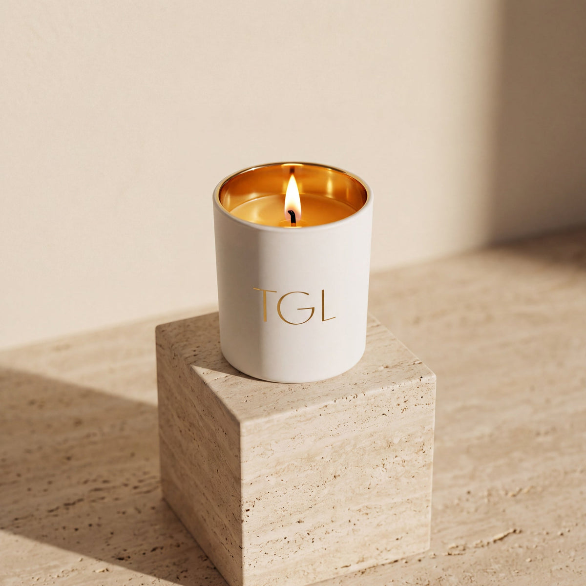 TGL soy candle by The GOOD LIFE, lit in a white jar on a travertine block