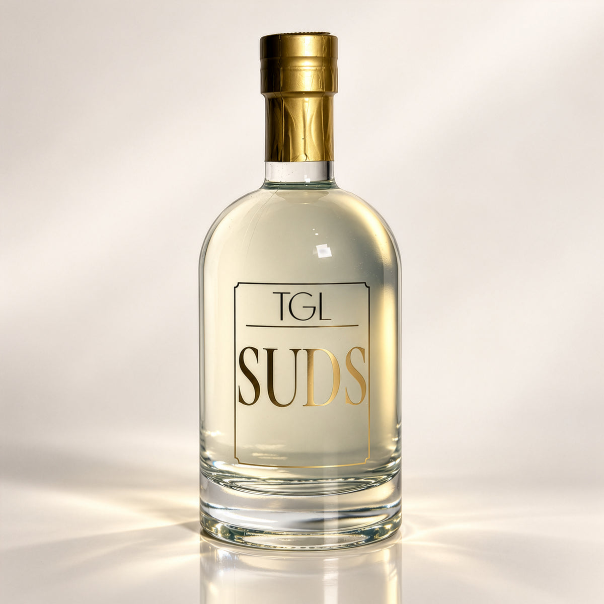 TGL SUDS foaming hand soap in an 18 oz glass bottle with gold label and gold foil top